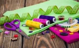 tissu-vert-bobines-de-fil-ciseaux-violets-aiguilles-table-bois